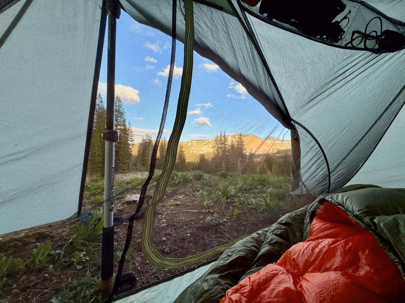 Looking out from inside a tent toward mountains at dusk.