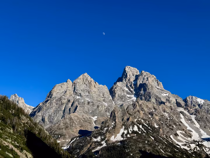 The Tetons from the North Fork of Cascade Canyon at dusk, the moon right above the peaks.