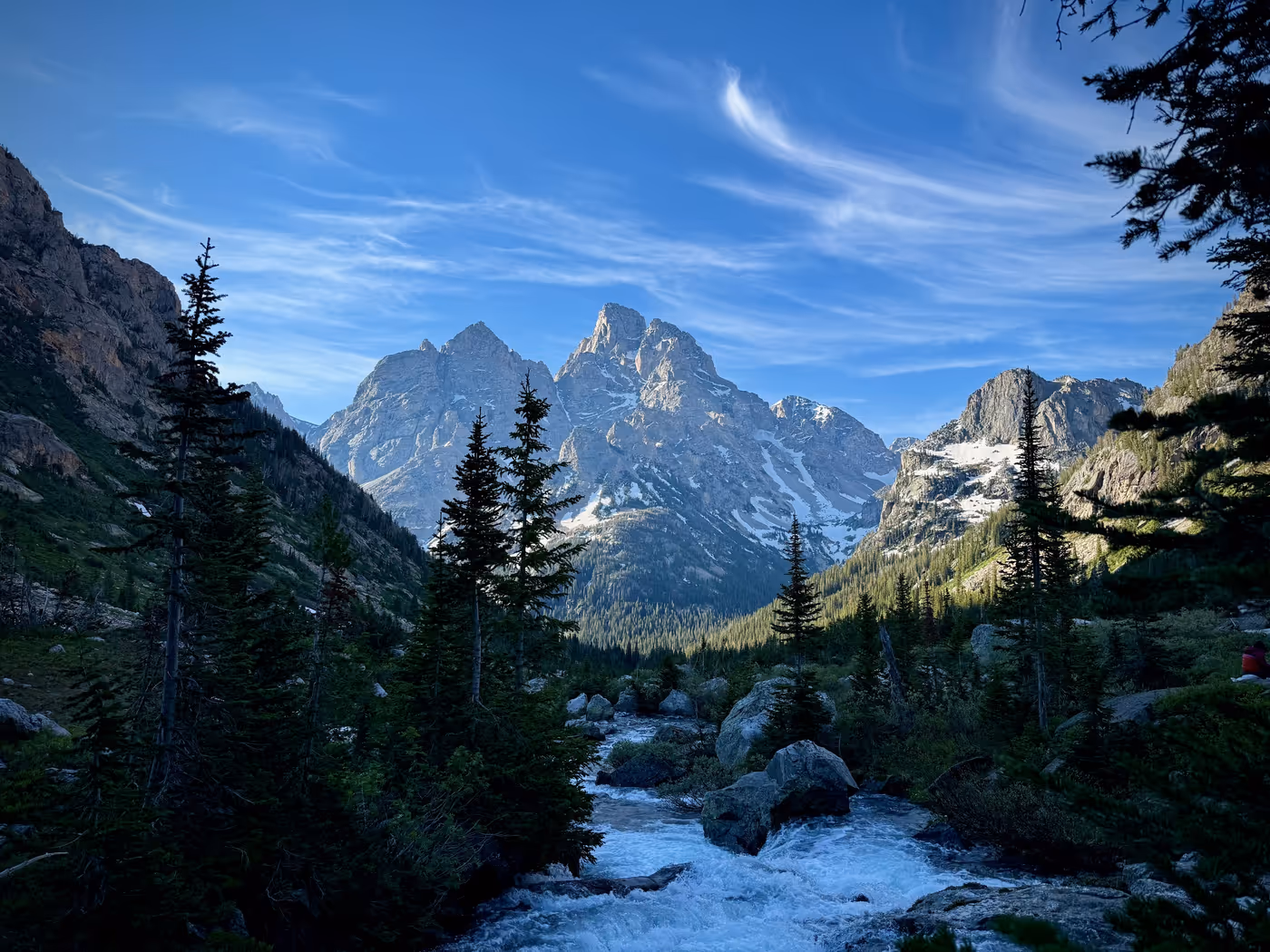 Sunlit mountain faces above a shadowed canyon at dawn.